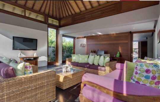 Living room area with comfy rattan couches and flat screen tv