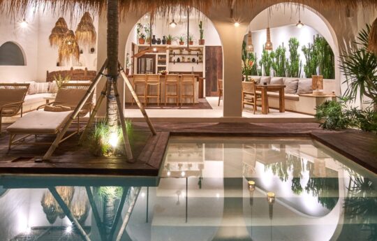 Villa living areas at night with lights on and swimming pool views