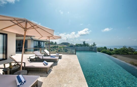 Lap swimming pool with day beds and sunbrella with ocean views