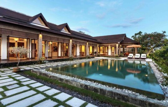 swimming pool and villa at sunset with lights on