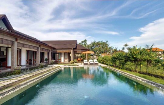Full length of swimming pool with garden and exterior villa views