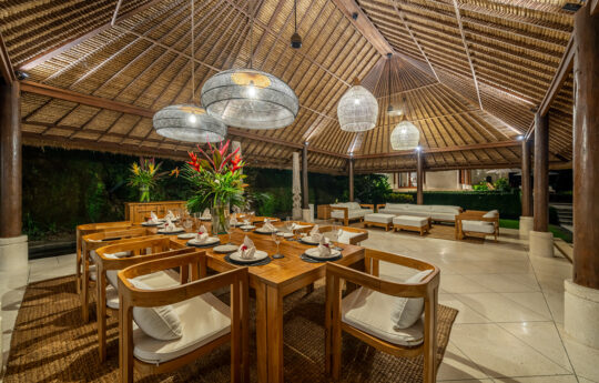 Dining table and comfortable sofa area under Bali style roof