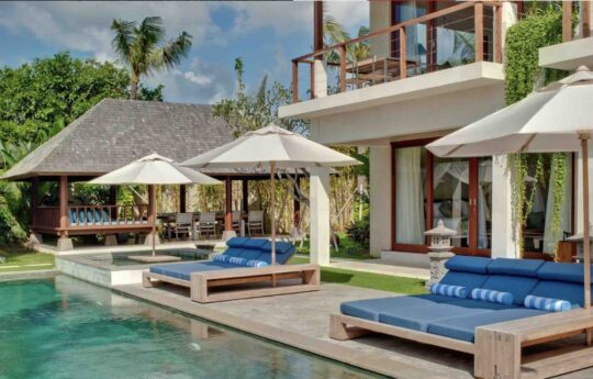 swimming pool with two days beds and sunbrellas on sunny day