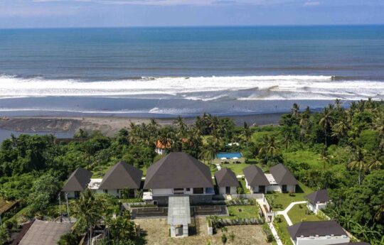 Aerial view of villa next to beach with expansive tropical gardens