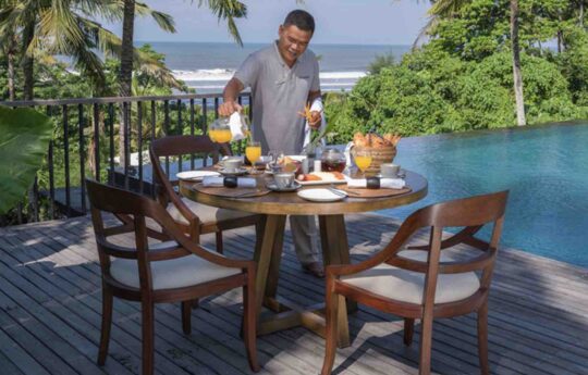 Balinese staff preparing breakfast by the pool in the villa