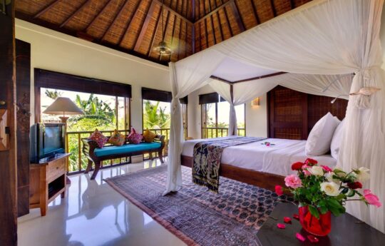 Large bedroom of villa with king bed with views to lush tropical garden