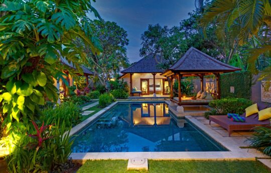 View of pool at dusk with garden and tropical plants