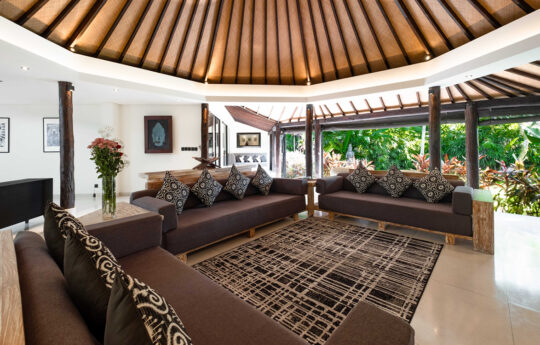 Living room area of villa with sofas, rugs and view to garden