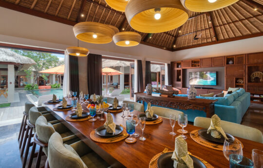 Dining table in villa with seats for 10 people with lounge room in background