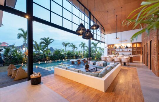 Open plan living area with sofa space and view to kitchen and swimming pool