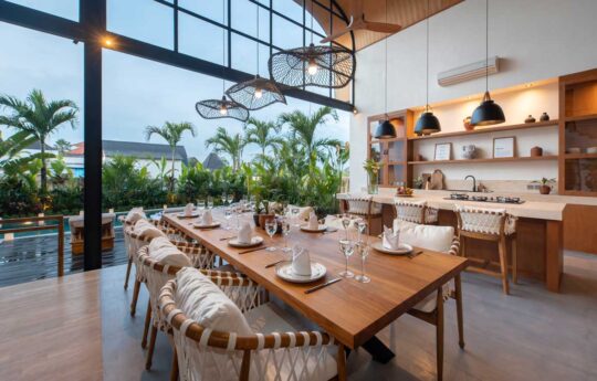 Dining table of villa with seating for eight people and kitchen area