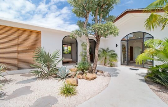 Villa entrance with paved walkway dotted with plants