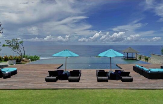 Ocean views as a backdrop with swimming pool and day days in foreground