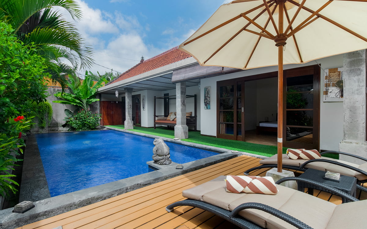 Swimming pool with day beds and umbrella in foreground