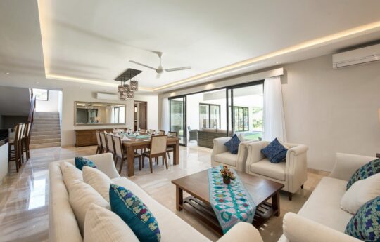 Modern open plan living area of villa with sofas and dining table.