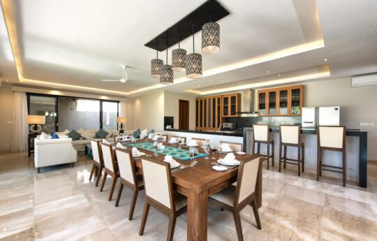 Formal dining table with seats for 10 people and kitchen in background