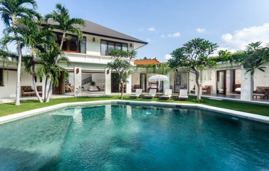 Swimming pool in the foreground with villa exterior in background on sunny day