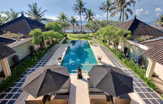 view of large bali villa on the beach with coconut trees