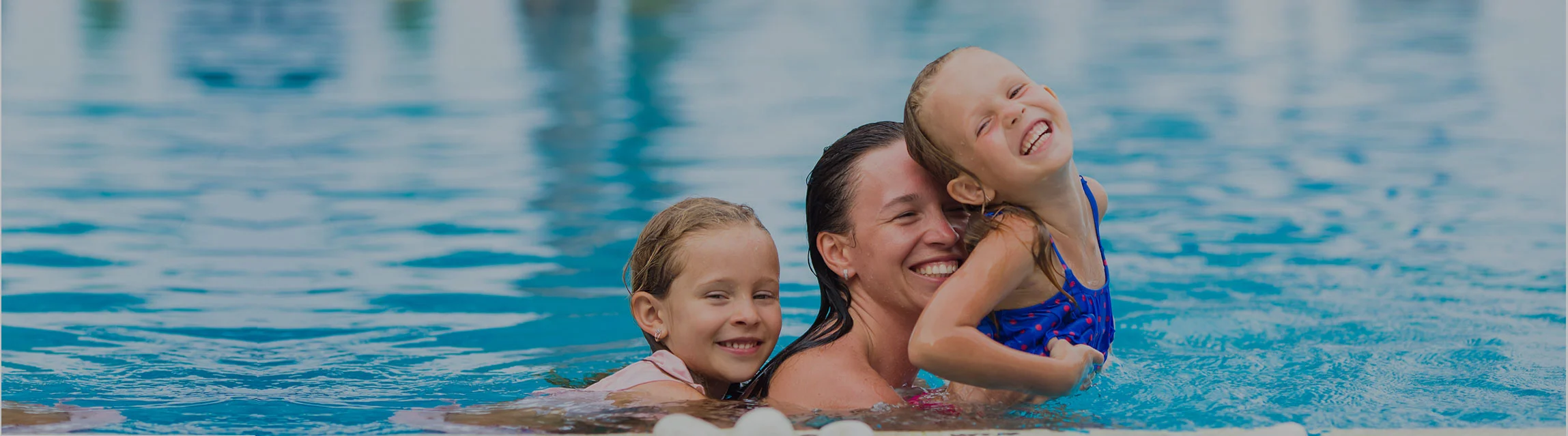 A mother with two children is swimming in a pool whilst on holiday in Bali